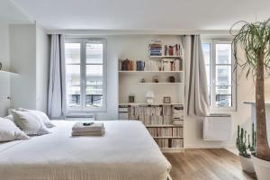 ein weißes Schlafzimmer mit einem großen weißen Bett und Bücherregalen in der Unterkunft Studio Tempa proche du Château de Vincennes - Welkeys in Vincennes