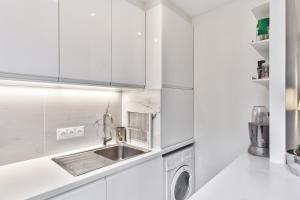 eine weiße Küche mit Spüle und Geschirrspüler in der Unterkunft Studio Tempa proche du Château de Vincennes - Welkeys in Vincennes + 4 Fotos