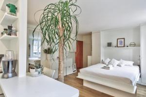 ein Schlafzimmer mit einem Bett und einer Palme darin in der Unterkunft Studio Tempa proche du Château de Vincennes - Welkeys in Vincennes
