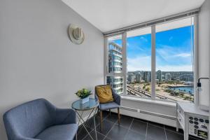 a living room with two chairs and a large window at Spacious DT 2-BDR High-rise with view, pool, gym in Vancouver