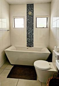 bagno bianco con vasca e servizi igienici di The Bridge, Apartment 25 a St Lucia