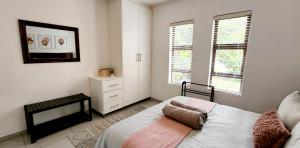 ein Schlafzimmer mit einem Bett, einer Kommode und zwei Fenstern in der Unterkunft The Bridge, Apartment 25 in St Lucia
