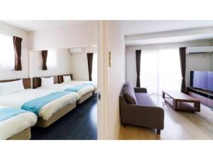 ein Hotelzimmer mit 2 Betten und einem Sofa in der Unterkunft Bears Stay Kumejima Eef Beach - Vacation STAY 85672v in Kumejima