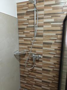 een douche in een badkamer met een houten muur bij Skott's Comfy Lodge in Bantayan