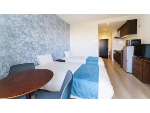 una camera d'albergo con due letti e un tavolo di Bears Stay Kumejima Eef Beach - Vacation STAY 85666v a Kumejima