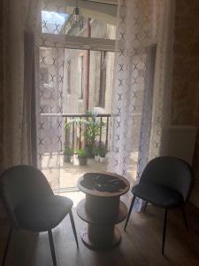 dwa krzesła i stół przed oknem w obiekcie Kamieniczka 12 Apartamenty Częstochowa w mieście Częstochowa