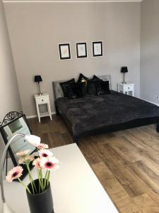 1 dormitorio con 1 cama negra y 2 mesas con flores en Kamieniczka 12 Apartamenty Częstochowa en Częstochowa