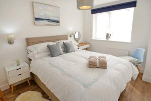ein Schlafzimmer mit einem großen weißen Bett mit Handtüchern darauf in der Unterkunft Seaside Annexe in Felpham