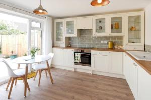 a kitchen with white cabinets and a table with chairs at Seaside Annexe in Felpham