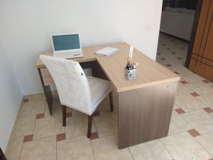 a wooden desk with a laptop and a chair at Sobrado Lindóia in Curitiba