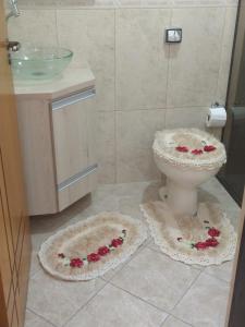 a bathroom with a toilet and flowers on the floor at Sobrado Lindóia in Curitiba