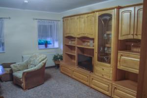 ein Wohnzimmer mit einem großen Holzschrank und einem Stuhl in der Unterkunft Pension Muldental Großbothen Wohnung 1 in Grimma