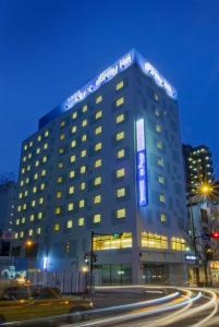 un grand bâtiment avec un panneau la nuit dans l'établissement Dormy Inn Hakata Gion, à Fukuoka