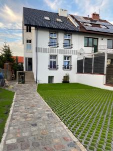 una casa con un césped verde delante de ella en Apartamenty Bezrzecze, en Szczecin