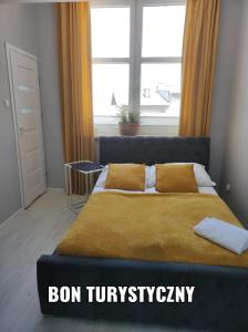 a bedroom with a bed with a yellow blanket and a window at MALTINA in Malbork