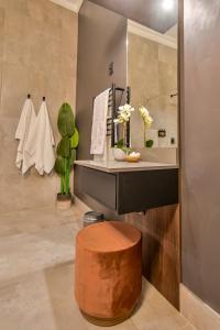 La salle de bains est pourvue d'un lavabo et d'un tabouret en bois. dans l'établissement Summer PALACE Guesthouse, à Bloemfontein