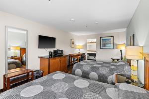a hotel room with two beds and a flat screen tv at Basecamp Puyallup in Puyallup