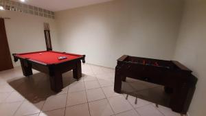 um quarto com uma mesa de bilhar vermelha e um piano em Pousada Anauê - Conde em Jacumã
