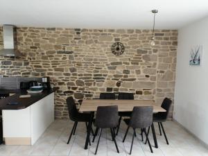 comedor con pared de piedra, mesa y sillas en Maison Jullouville au calme, en Jullouville-les-Pins