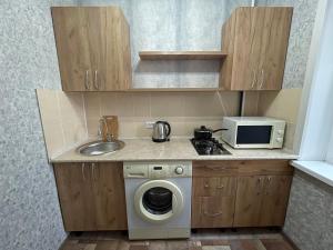 una pequeña cocina con fregadero y lavadora en 1-комнатная квартира в центре!, en Petropavlovsk