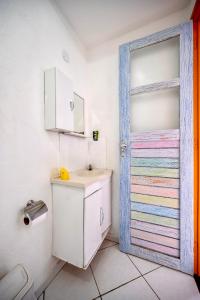 baño con lavabo y puerta colorida en Pousada Água Marinha-Familias & Pets en Angra dos Reis