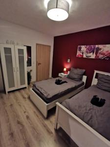 1 Schlafzimmer mit 2 Betten und einer roten Wand in der Unterkunft Liebevoll eingerichtete Ferienwohnung - Zentrale Lage - Netflix & Paytv in Wilhelmshaven