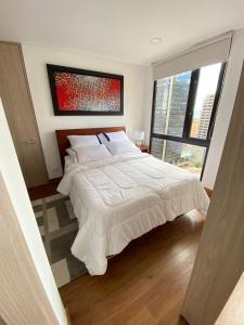 een slaapkamer met een groot wit bed en een raam bij Apartamento Bogota Centro Internacional in Bogota