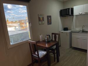 una pequeña cocina con mesa, sillas y ventana en Loft & Suites Centro, en Salto
