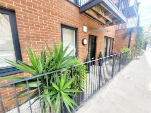 a fence in front of a brick building with plants at The ascension 'Ascalon ' in London +2 photos