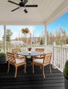 a table and chairs on a porch with a ceiling fan at The Lenox Collection in Lenox