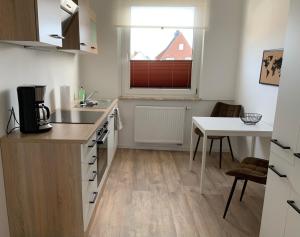 a kitchen with a sink and a table and a window at FEDDERSEN LIVING Moderne Ferienwohnungen - Gemütlich - Netflix - Voll ausgestattet - Waschmaschine - zentral gelegen in Brunsbüttel