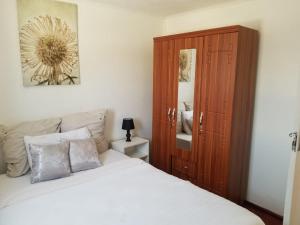 a bedroom with a bed and a wooden cabinet at Samkab Legacy & Comfort in Lusaka