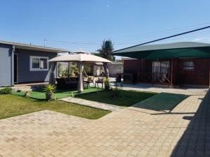 a patio with an umbrella and a house at Samkab Legacy & Comfort in Lusaka