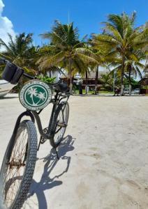 una bicicleta estacionada en la playa con palmeras en el fondo en Palmeras de Mahahual Cabañas, en Mahahual