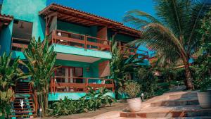 a blue house with palm trees in front of it at Cores do Arraial Residence Hotel in Arraial d'Ajuda