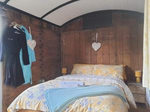 a bedroom with a bed with a wooden wall at Luxury cosy carriage with electric private hot tub in Hereford