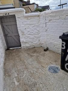 a brick wall with a garage door and a trash can at Violet House in Derry Londonderry