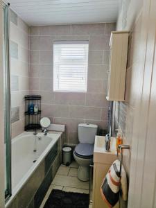 a bathroom with a toilet and a tub and a sink at Violet House in Derry Londonderry +2 photos