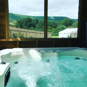 a jacuzzi tub in front of a window at Luxury cosy carriage with electric private hot tub in Hereford