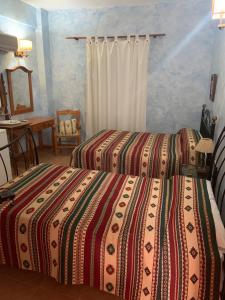 a bedroom with two beds and a table and a mirror at Hotel Azabache in Arboleas