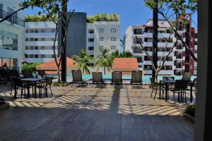 a patio with tables and chairs and a pool at Steps from the Beach Condo Life Bucerias Golden Zone in Bucerías