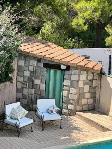 dwa krzesła na patio obok budynku w obiekcie Le clos Roby maison avec piscine proche du centre historique w mieście Pézenas