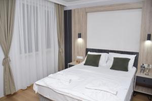 a bedroom with a large white bed with green pillows at Hotel Arinna in Istanbul