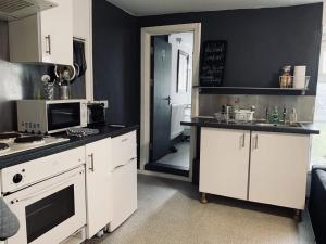 a kitchen with white cabinets and a stove and a microwave at 40 Carlton Tce F1 in Swansea