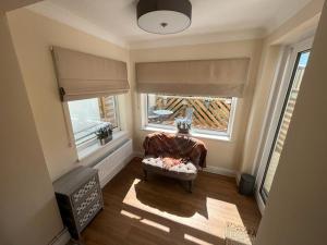 a living room with a chair and two windows at Cosy cottage with beautiful mountain views in Blaenavon