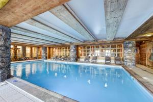 a swimming pool in a building with chairs and a library at Résidence Pierre & Vacances Premium Le Roselend in Arc 1800 +50 photos