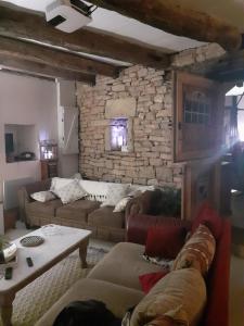 a living room with couches and a stone wall at La grange in Promilhanes