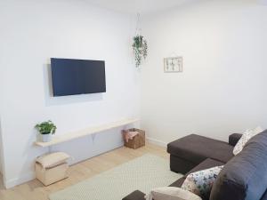 een woonkamer met een bank en een tv aan de muur bij A Capelada-Céntrico apartamento en Cedeira in Cedeira