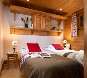 a bedroom with two beds with red pillows and a book at Résidence Pierre & Vacances Premium Le Roselend in Arc 1800