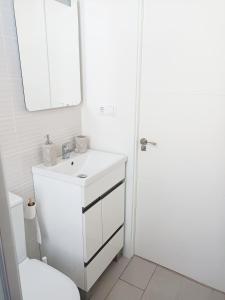 een witte badkamer met een wastafel en een spiegel bij A Capelada-Céntrico apartamento en Cedeira in Cedeira